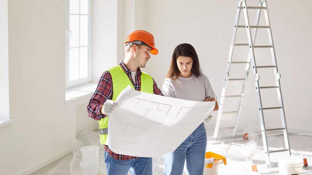 Contractor and homeowner reviewing renovation blueprint together indoors