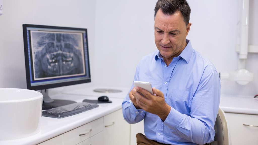 Dentist checking practice reviews and messages between patient appointments