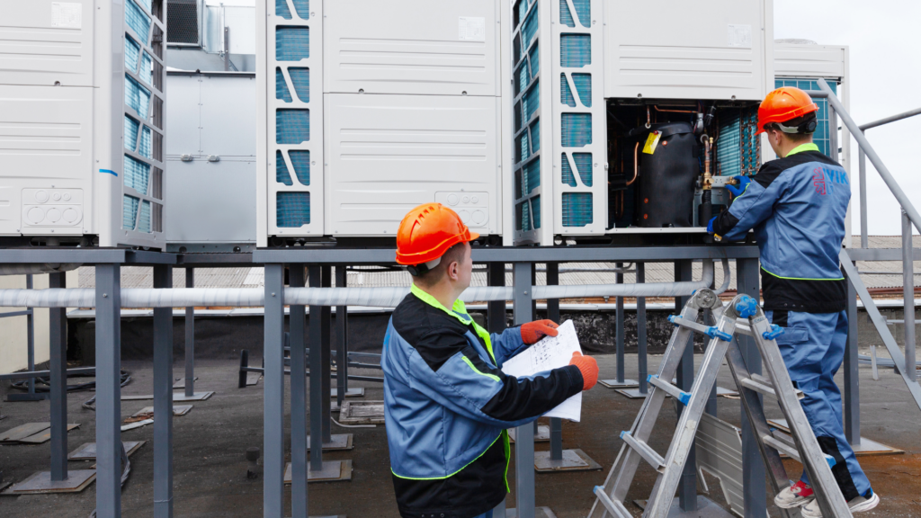 Two HVAC workers inspecting commercial rooftop cooling equipment together