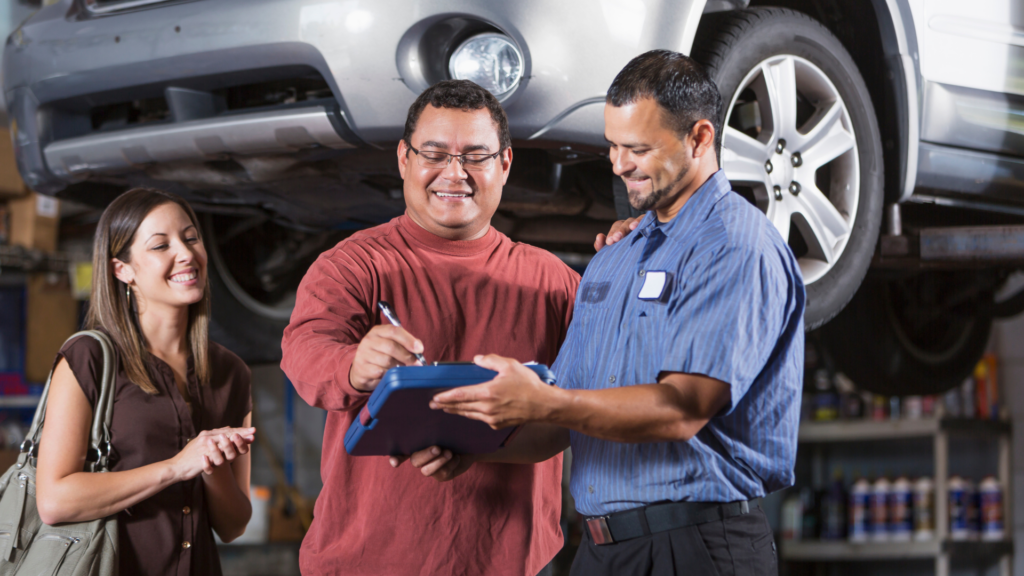 Mechanic explaining vehicle repair checklist to satisfied customers