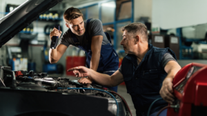 Mechanics collaborating on engine repair inside auto shop
