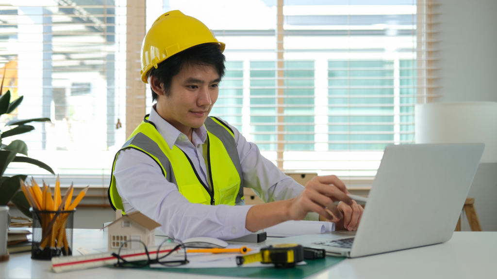 Architect checking client reviews on a laptop beside a house model