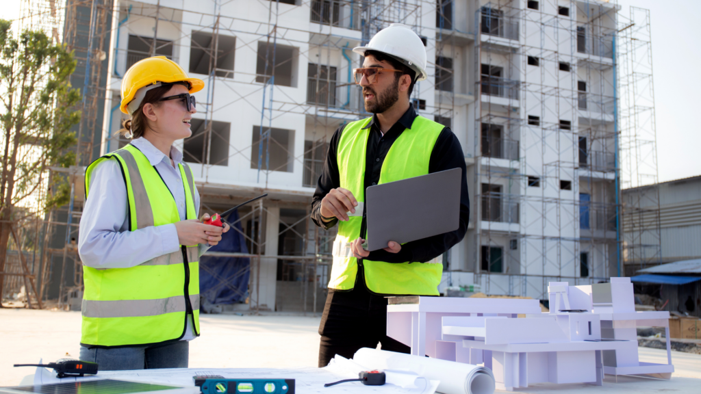 Architects discussing a building project on site with a laptop and models