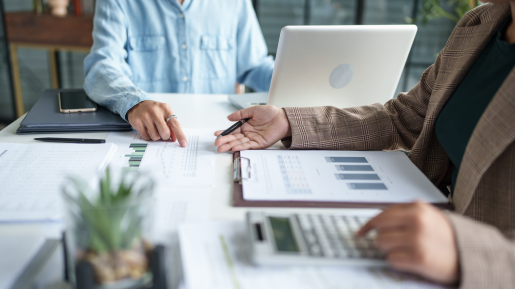 Coworkers comparing printed charts while preparing business information for an audit