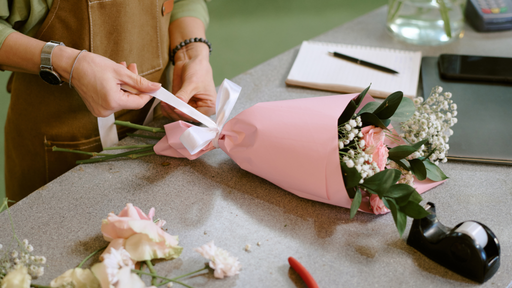 Florist wrapping a fresh bouquet at the shop counter for a holiday