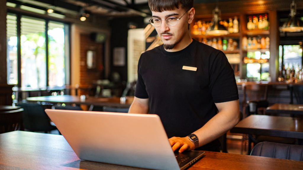 Franchise employee updating local branch content on a laptop at a restaurant