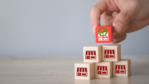 Hand stacking storefront blocks to represent SEO for franchises across many locations