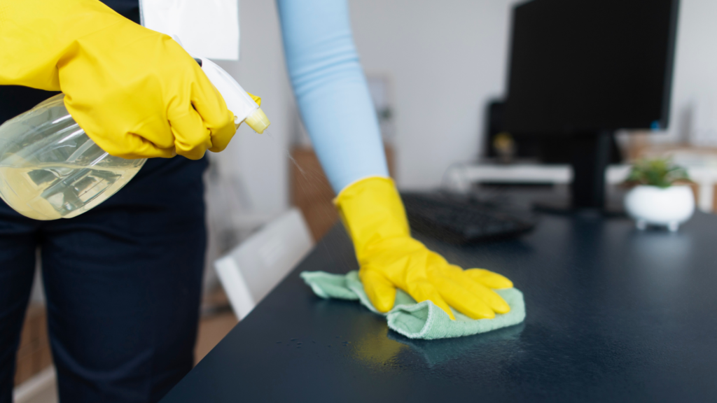 Local cleaning professional wiping down a desk during a home office cleaning service