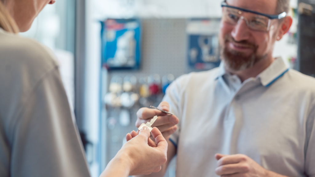 Locksmith handing a new key to a smiling customer in his shop