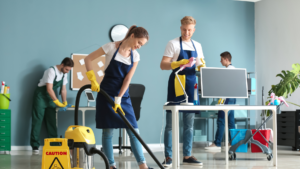 Professional cleaning team vacuuming and wiping desks in a modern office