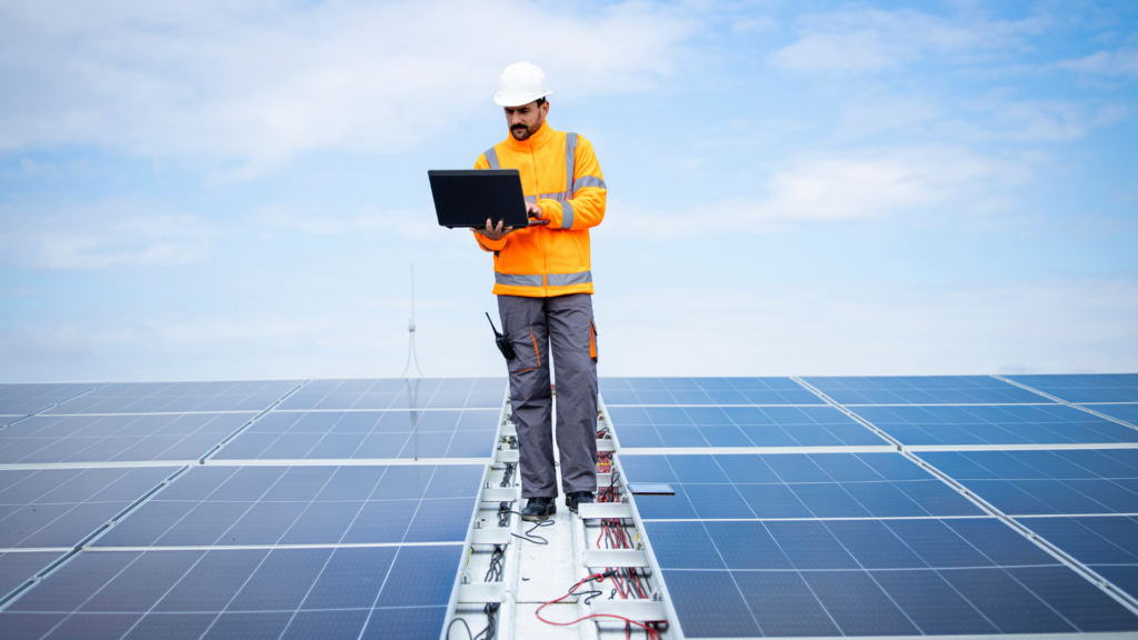 Solar installer reviewing customer feedback on a laptop atop rooftop panels
