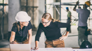 Two architects reviewing blueprints together to plan a new building project