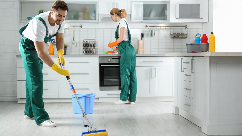 Two trusted house cleaners in uniform finishing a kitchen cleaning job
