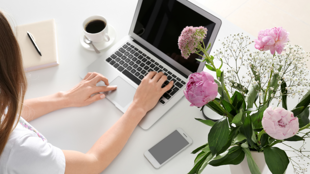 Woman reading customer reviews on a laptop next to fresh flowers